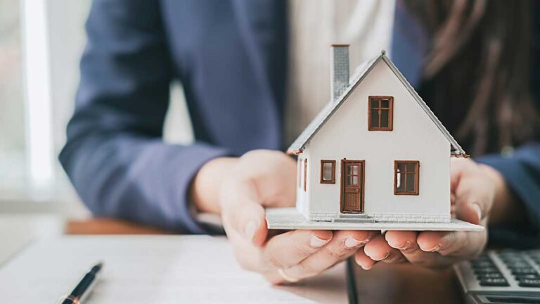A family reviews home purchase documents at a dining room table with a real estate folder and coffee mugs.